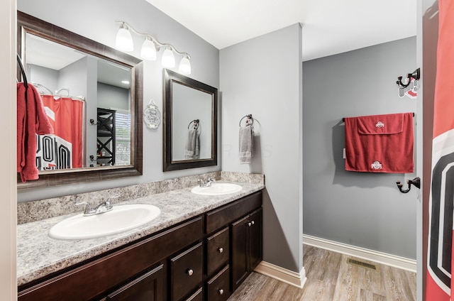 bathroom featuring double vanity, visible vents, a sink, and wood finished floors