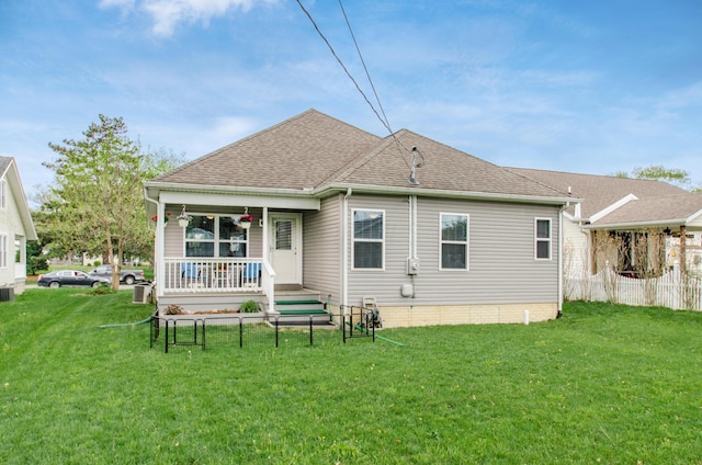 back of house featuring a yard, a shingled roof, and a porch