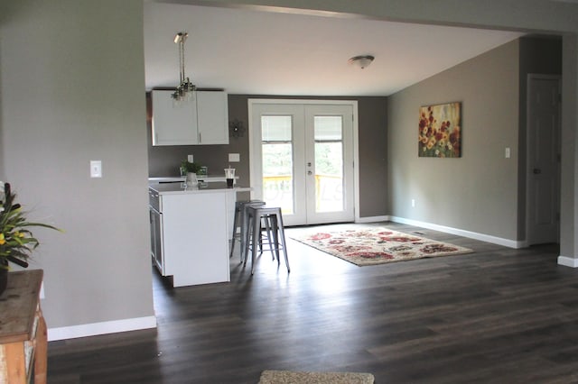 kitchen featuring french doors, baseboards, white cabinetry, and a kitchen bar