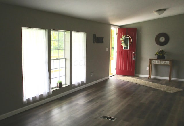 unfurnished living room with baseboards, visible vents, and wood finished floors