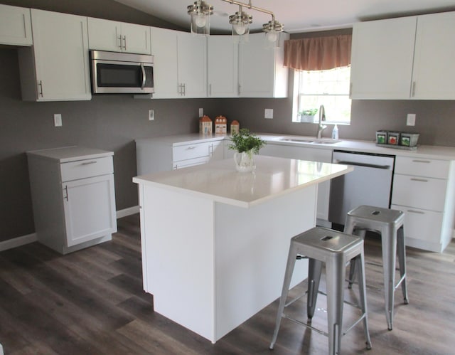 kitchen featuring white cabinets, a sink, stainless steel microwave, dark wood-type flooring, and dishwashing machine
