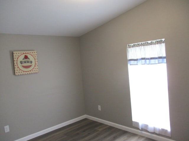 spare room featuring baseboards and dark wood-style flooring