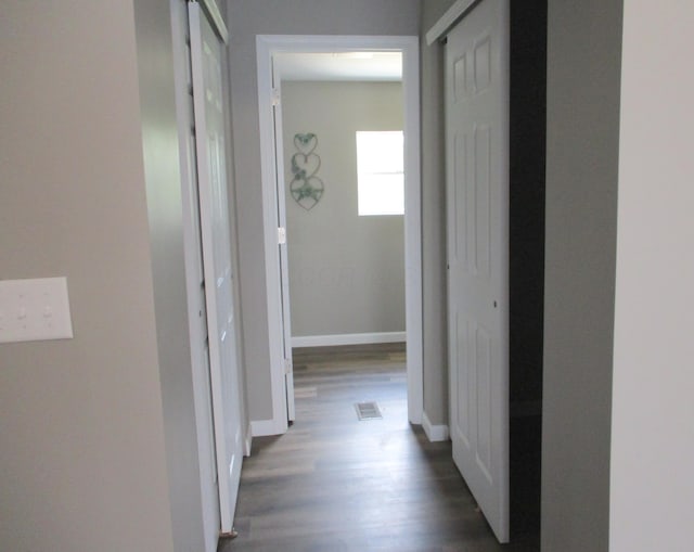 hall featuring baseboards, visible vents, and dark wood-style floors
