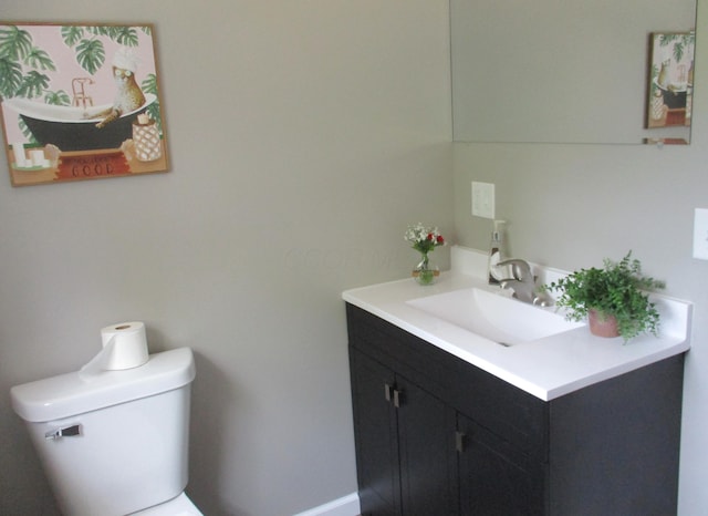 bathroom with toilet, baseboards, and vanity