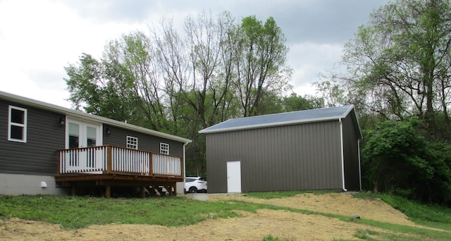 rear view of property featuring a wooden deck and an outdoor structure