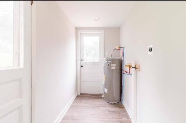 doorway with baseboards, light wood-type flooring, a healthy amount of sunlight, and electric water heater