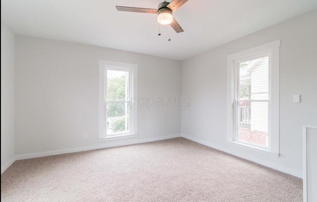 unfurnished room with light colored carpet, baseboards, and ceiling fan