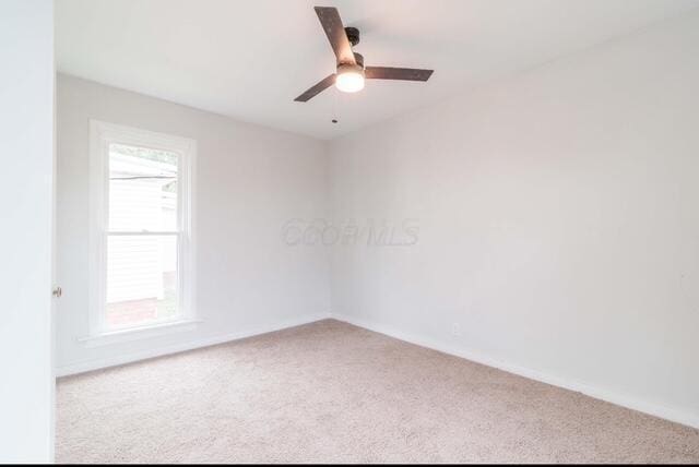 carpeted empty room with baseboards and a ceiling fan