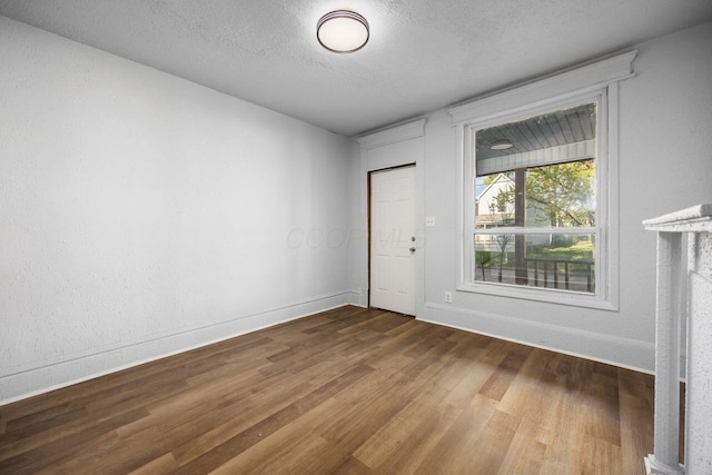 unfurnished room featuring baseboards, a textured ceiling, and wood finished floors