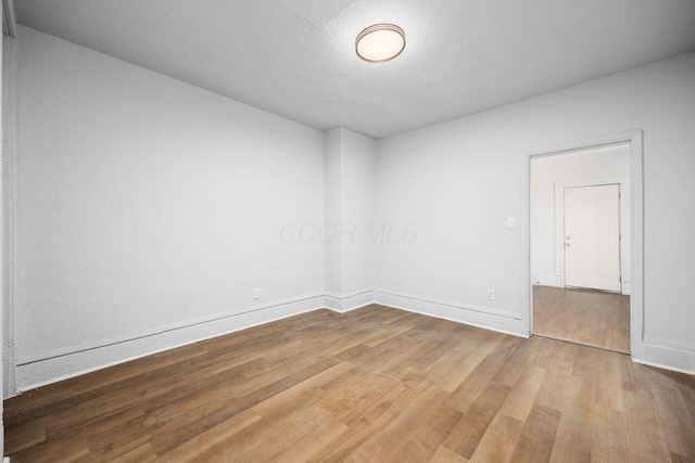 unfurnished room with baseboards, a textured ceiling, and wood finished floors