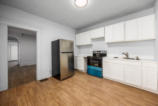 kitchen featuring a sink, light wood-style floors, black electric range oven, freestanding refrigerator, and visible vents