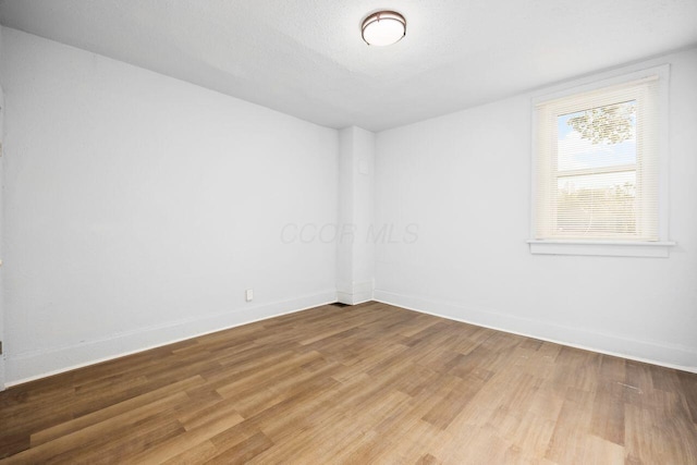 empty room with baseboards and light wood-style floors