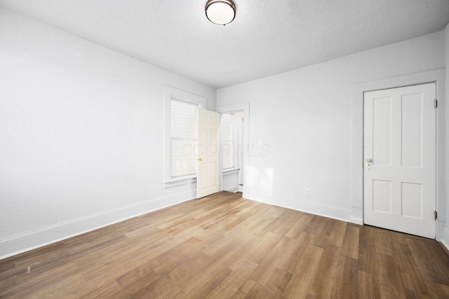 unfurnished bedroom featuring a textured ceiling, baseboards, and wood finished floors