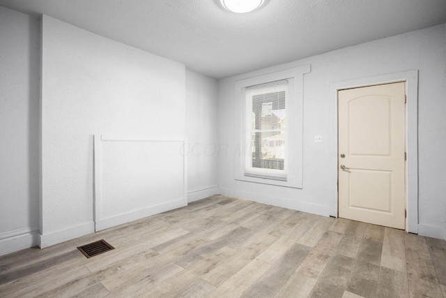 unfurnished room with baseboards, visible vents, and light wood-style flooring