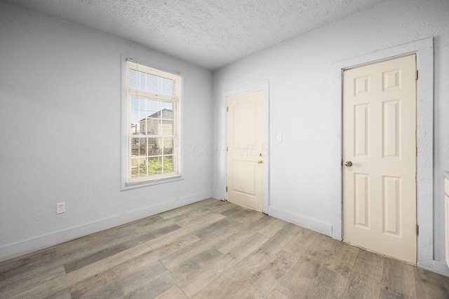 empty room with baseboards, a textured ceiling, and wood finished floors