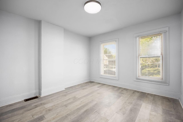 empty room with visible vents, baseboards, and wood finished floors