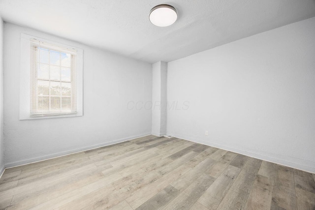 spare room featuring baseboards, a textured ceiling, and wood finished floors