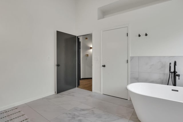 845 Mcnaughten Rd, Columbus, OH 43213 - full bath with tile walls, baseboards, a soaking tub, and marble finish floor