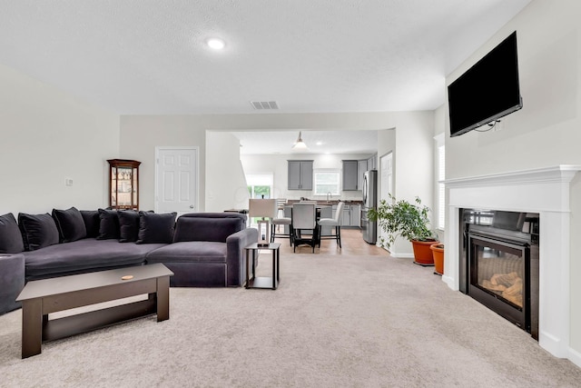 5837 Mouzon Dr, Columbus, OH 43232 - living room featuring visible vents, baseboards, a glass covered fireplace, and light carpet