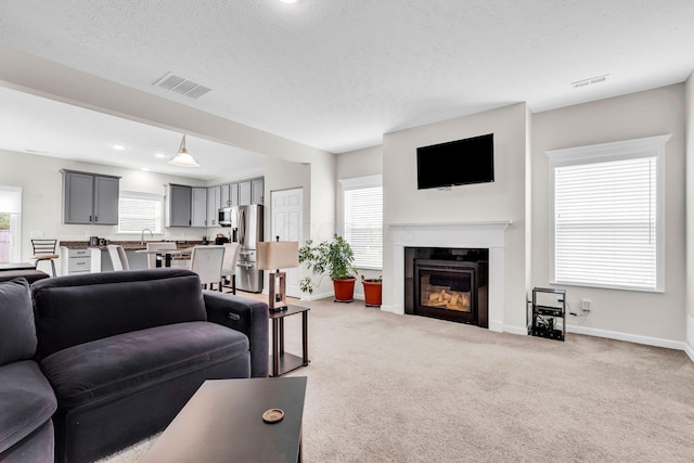 5837 Mouzon Dr, Columbus, OH 43232 - living room featuring a textured ceiling, baseboards, a glass covered fireplace, visible vents, and light carpet