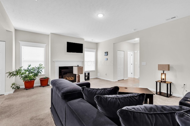 5837 Mouzon Dr, Columbus, OH 43232 - living room with light colored carpet, a textured ceiling, visible vents, baseboards, and a glass covered fireplace