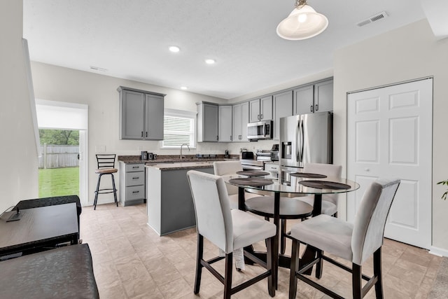5837 Mouzon Dr, Columbus, OH 43232 - kitchen featuring gray cabinetry, visible vents, a sink, a kitchen island, and appliances with stainless steel finishes
