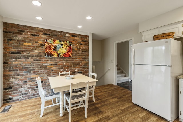 4522 Crompton Dr, Columbus, OH 43220 - dining area with wood finished floors, recessed lighting, stairs, and brick wall