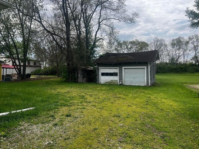 view of yard featuring a detached garage, central AC unit, and an outdoor structure