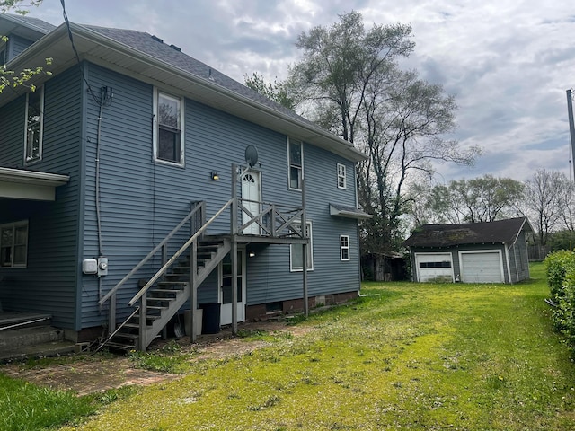 back of property with a garage, an outdoor structure, and a lawn