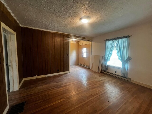 spare room featuring a textured ceiling, a baseboard radiator, wood finished floors, and visible vents