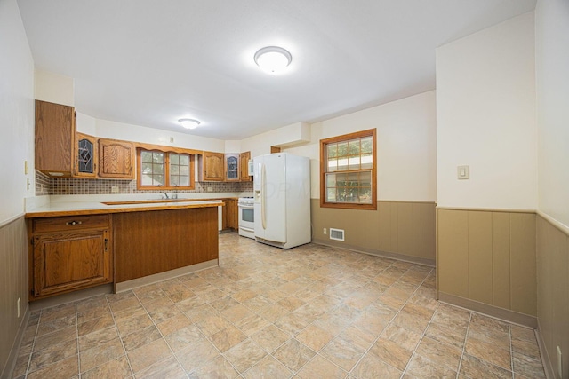 125 S Hamilton Rd, Columbus, OH 43230 - kitchen with white appliances, brown cabinetry, stone finish floors, a peninsula, and a wainscoted wall