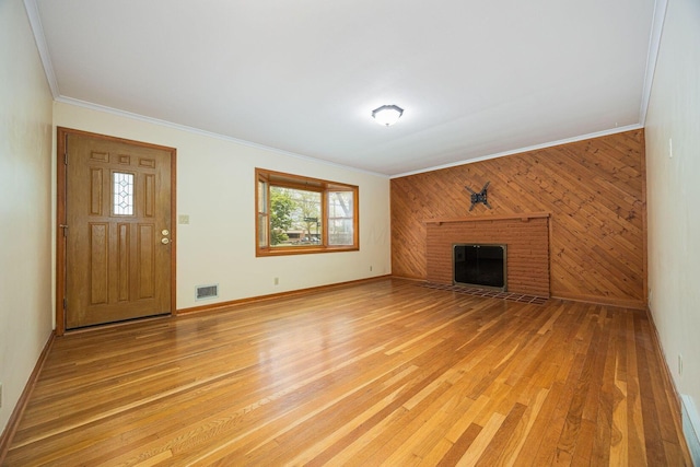 125 S Hamilton Rd, Columbus, OH 43230 - unfurnished living room featuring crown molding, light wood-style flooring, a brick fireplace, wooden walls, and baseboards