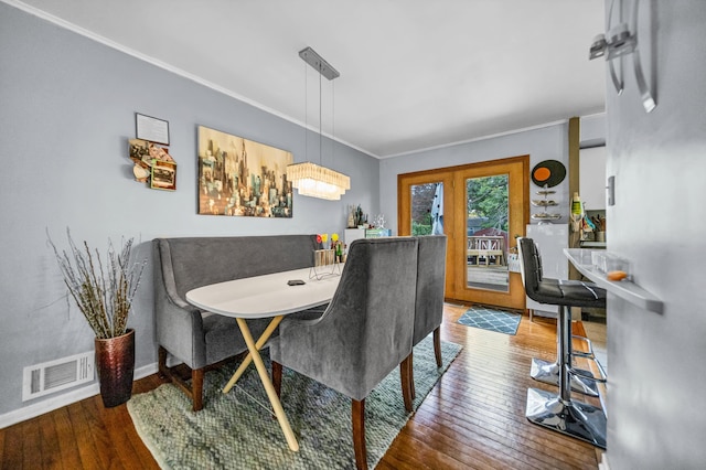 dining area featuring visible vents, ornamental molding, wood-type flooring, and baseboards