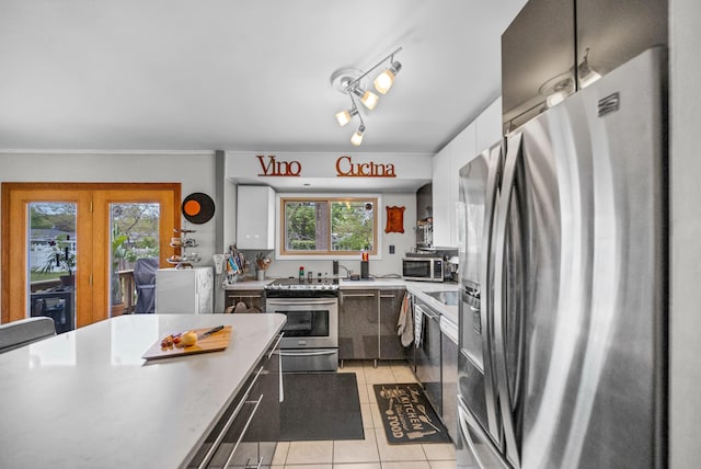 kitchen featuring appliances with stainless steel finishes, light countertops, white cabinetry, light tile patterned floors, and modern cabinets