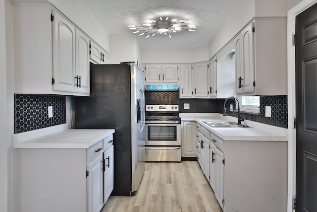 1235 Beechwood Rd, Columbus, OH 43227 - kitchen featuring under cabinet range hood, stainless steel appliances, light wood finished floors, a textured ceiling, and decorative backsplash