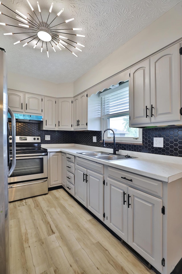 1235 Beechwood Rd, Columbus, OH 43227 - kitchen featuring appliances with stainless steel finishes, under cabinet range hood, light wood-type flooring, tasteful backsplash, and a textured ceiling