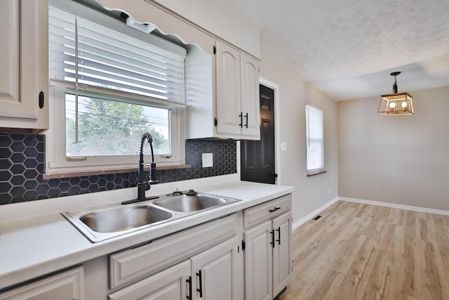 1235 Beechwood Rd, Columbus, OH 43227 - kitchen featuring white cabinets, backsplash, pendant lighting, light wood-style flooring, and light countertops