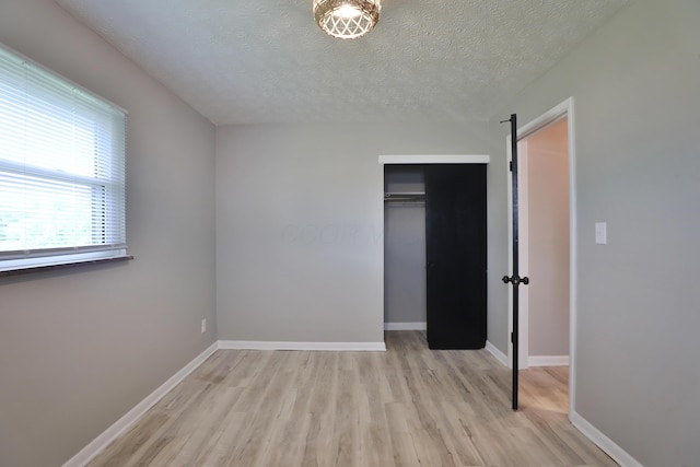 1235 Beechwood Rd, Columbus, OH 43227 - unfurnished bedroom with light wood-style floors, a closet, a textured ceiling, and a barn door