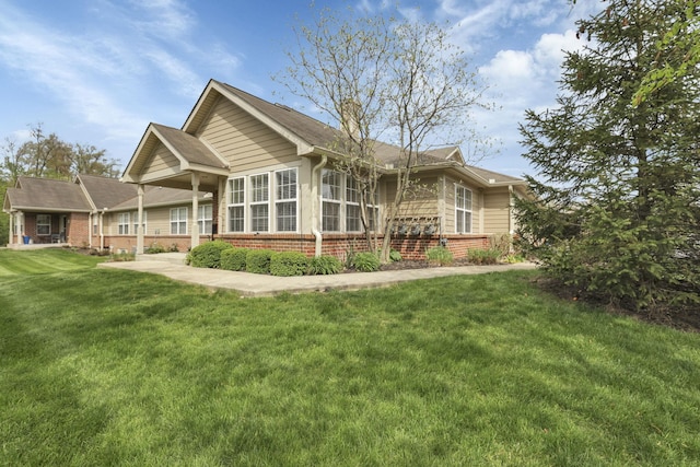 back of property featuring brick siding and a lawn