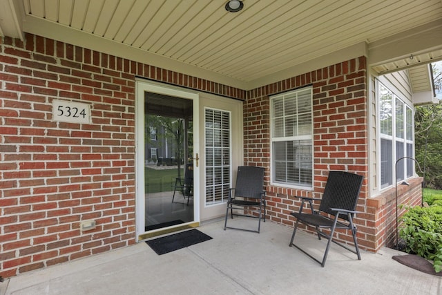 property entrance with brick siding and a patio