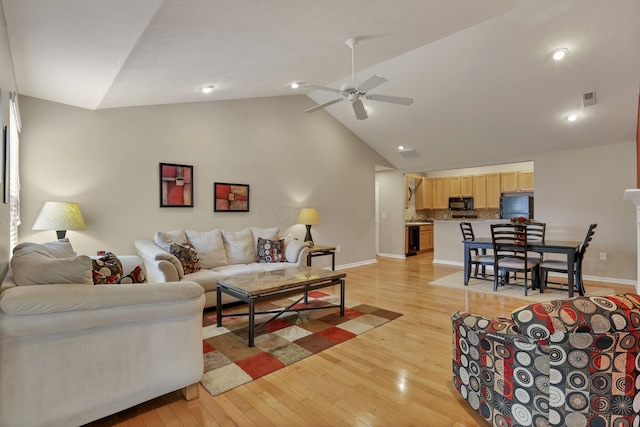 living room with light wood-style floors, a ceiling fan, baseboards, recessed lighting, and vaulted ceiling