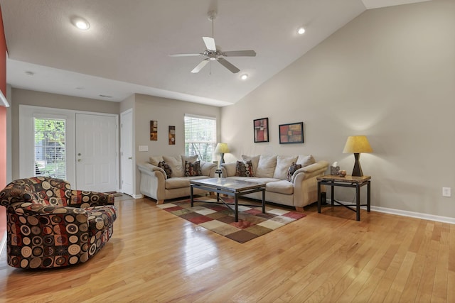 living room featuring ceiling fan, vaulted ceiling, a wealth of natural light, and light wood-style flooring