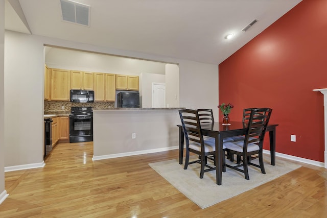 dining space with visible vents, vaulted ceiling, and light wood-style floors