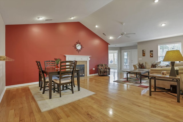 dining space featuring a ceiling fan, visible vents, a fireplace, baseboards, and light wood-style flooring