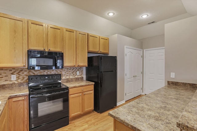 kitchen featuring visible vents, light wood-style flooring, backsplash, and black appliances