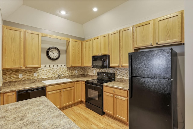 kitchen with a sink, light brown cabinets, black appliances, and light wood-type flooring