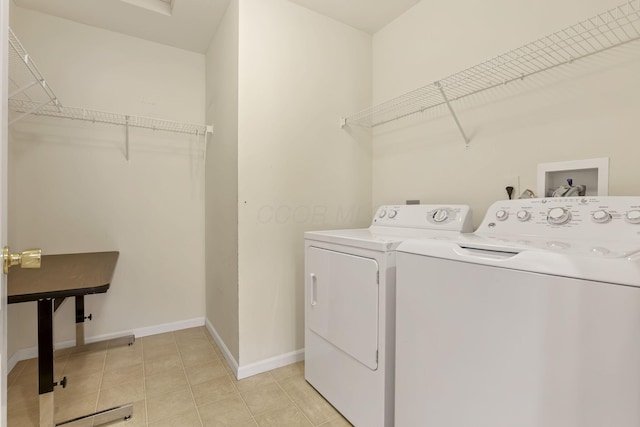 washroom featuring washing machine and clothes dryer, light tile patterned floors, laundry area, and baseboards