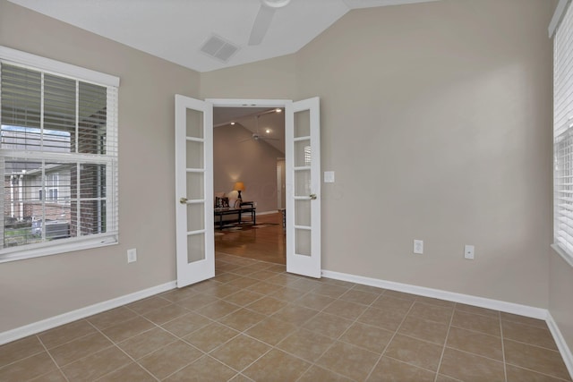 tiled empty room with ceiling fan, visible vents, french doors, a wealth of natural light, and vaulted ceiling