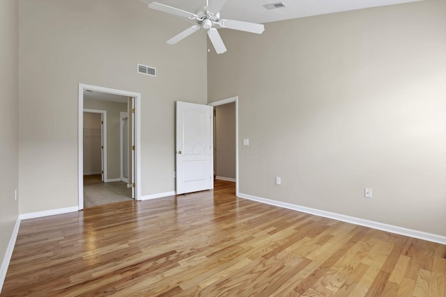 unfurnished bedroom with light wood-style floors, visible vents, baseboards, and a towering ceiling