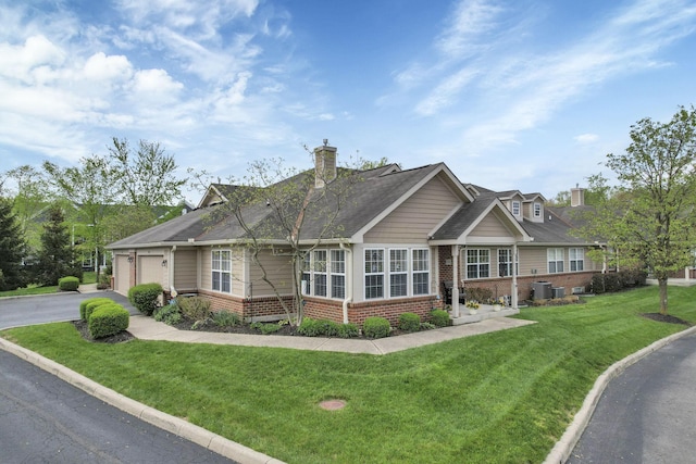 view of front of home with an attached garage, driveway, a front lawn, and brick siding